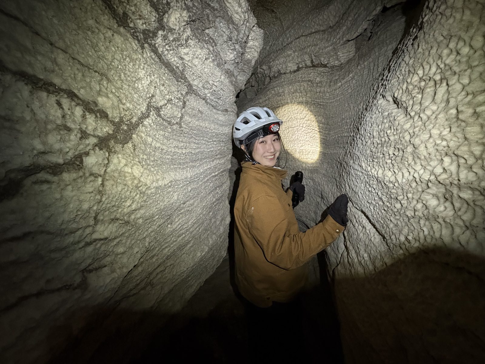 Selina caving in a lava tube, headlamp on