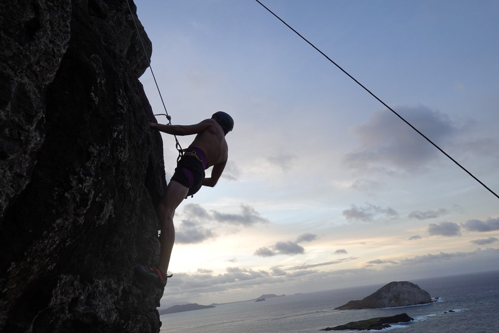 Climbing a sea cliff at dusk at Makapu'u, with Manana (Rabbit Island) in the distance